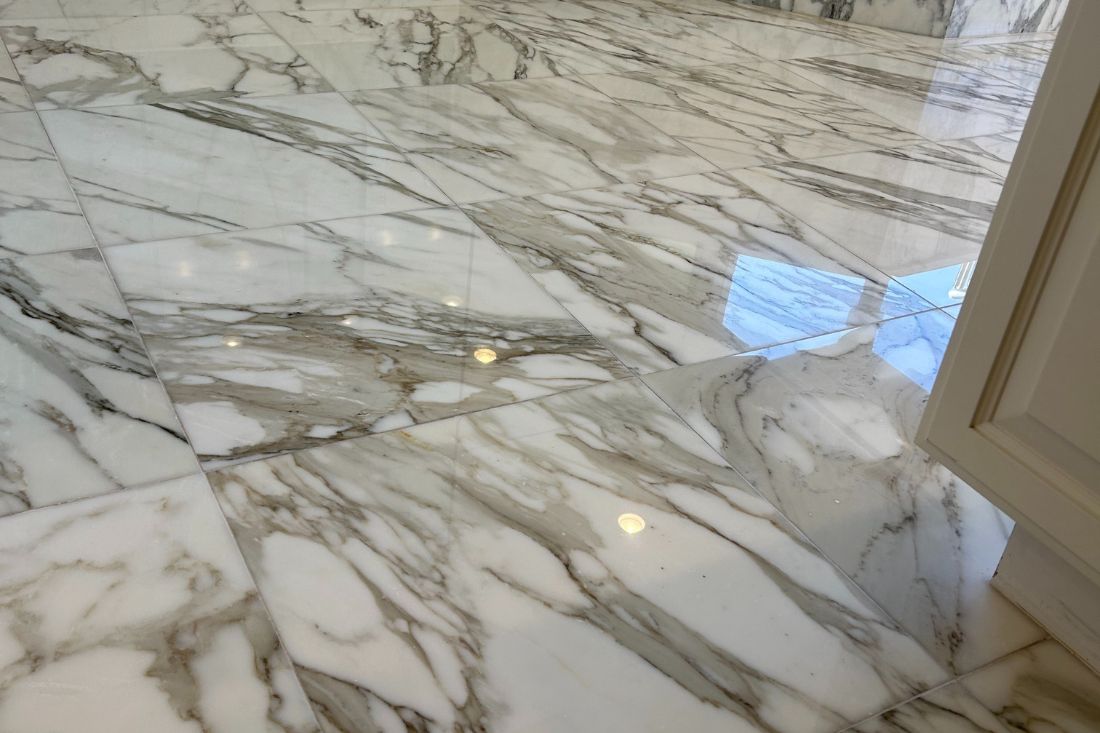 After photo of StoneShine's marble floor restoration in a Laguna Beach bathroom. The marble surface now features a high-gloss, reflective finish that enhances the natural veining and brings a luxurious, refreshed look to the space.