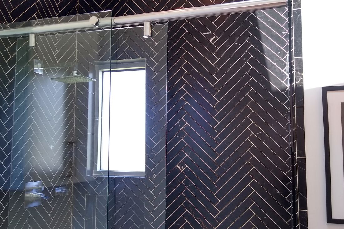 After photo of StoneShine's marble shower wall cleaning and sealing service in Beverly Hills. The black marble herringbone wall now features a restored, polished finish with enhanced shine and contrast.