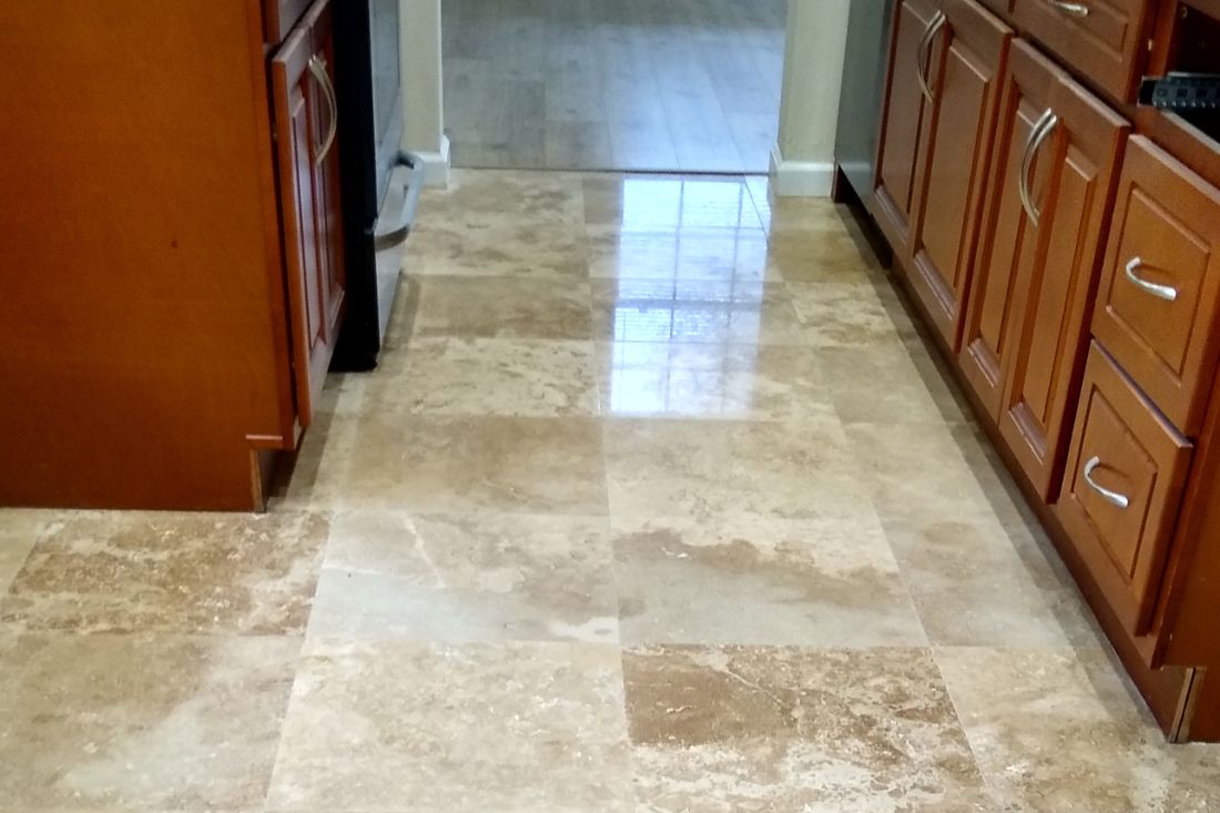 After photo of StoneShine's travertine floor restoration service in a San Clemente kitchen. The natural stone tiles are polished to a smooth and reflective finish.