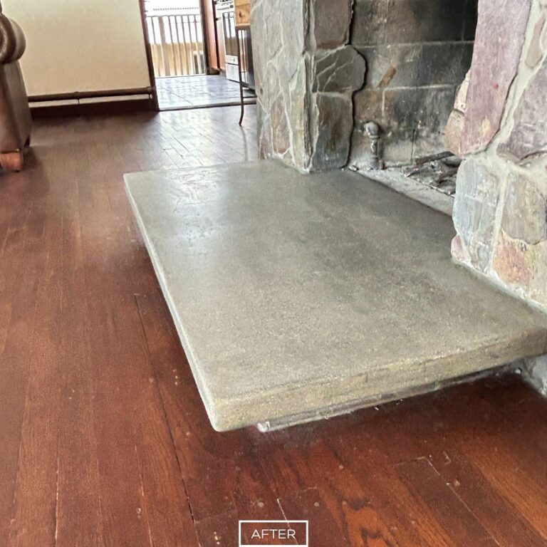 Ground concrete hearth in Laguna Beach home showing clean finish next to stone fireplace.
