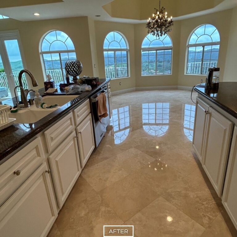 After travertine floor restoration in Diamond Bar showcasing a smooth, polished finish in the kitchen area with crystal-clear reflections of the arched windows and chandelier.