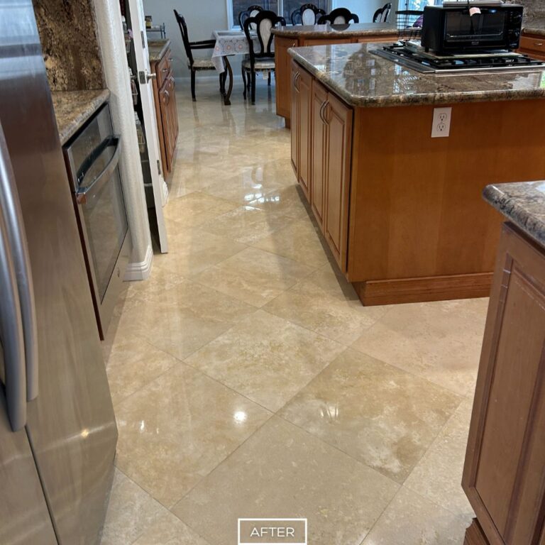 Shiny travertine floor after restoration in spacious Palm Desert kitchen with island and dining view.