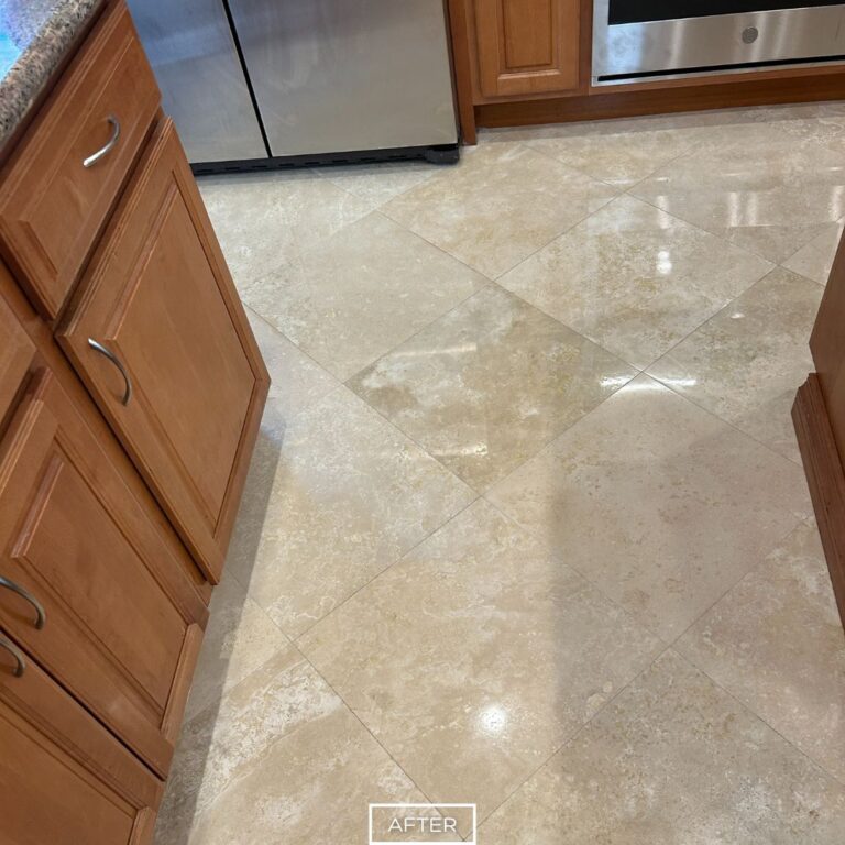 Glossy travertine tiles restored in Palm Desert kitchen near stainless appliances and wooden cabinets.
