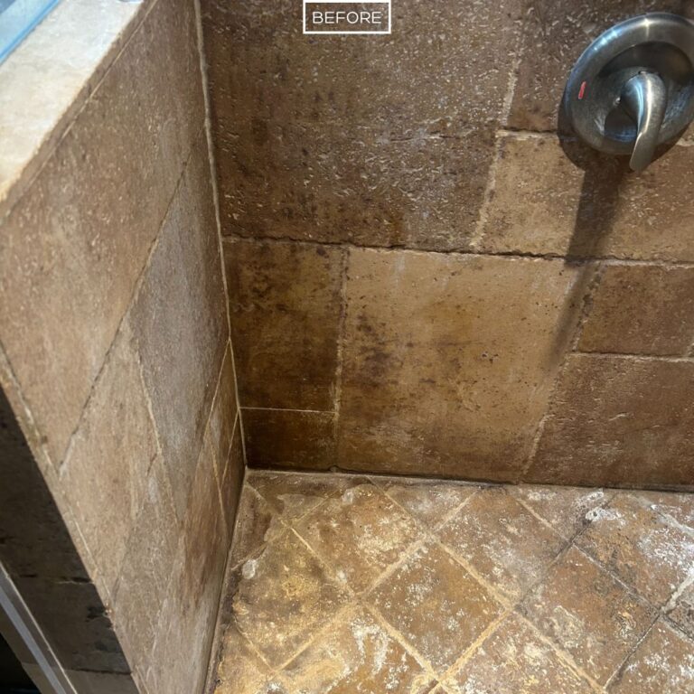 Stained travertine shower tiles and grout lines before restoration in La Habra Heights