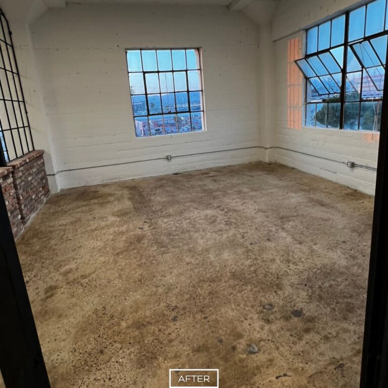 Smooth concrete floor in Los Angeles loft after grinding, showcasing a clean and even surface in a bright corner room.