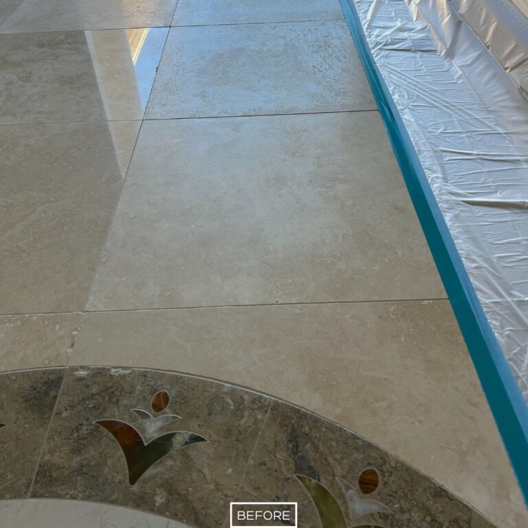 Dull travertine tile with etched surface and decorative inlay before restoration in Newport Beach