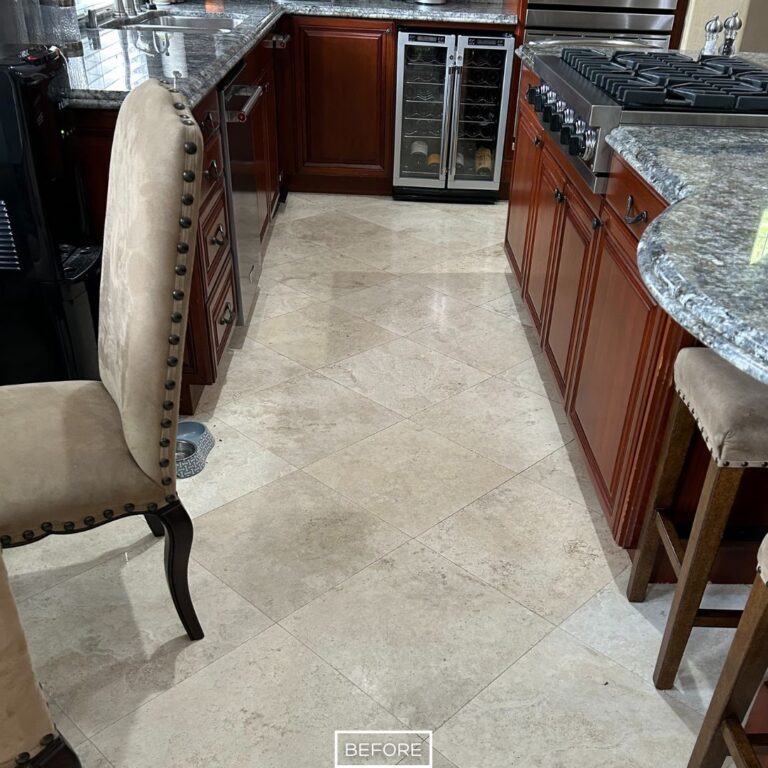 Before travertine floor restoration in San Clemente kitchen, showing dull and stained tiles near cabinets and countertops.