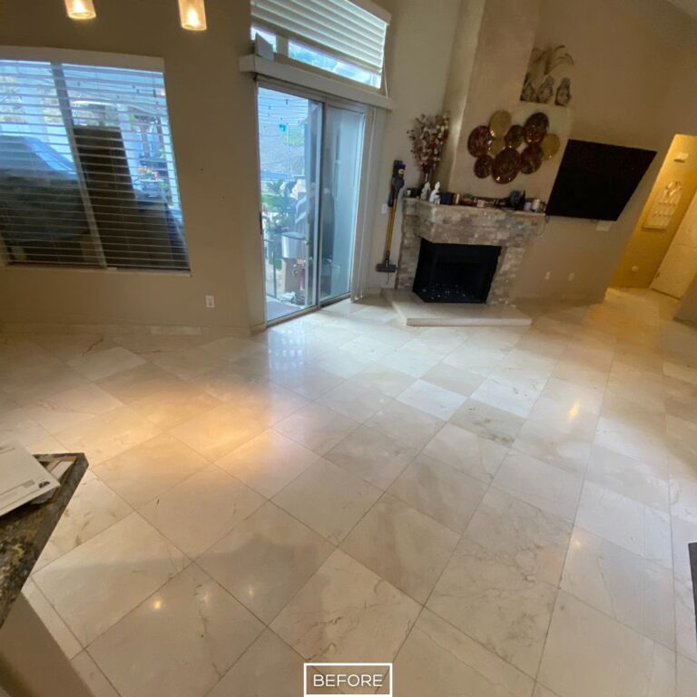 Worn marble flooring in Los Angeles home before restoration, showing lack of shine and uneven appearance near fireplace.