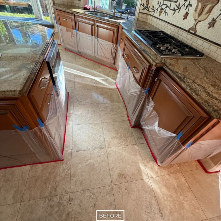 Etched and uneven travertine flooring near kitchen counters in Beverly Hills, covered surfaces protected before stone refinishing.