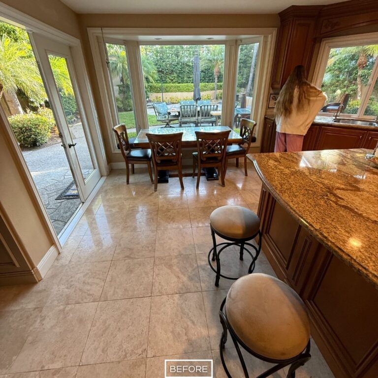 Dull travertine floor in a Beverly Hills dining area before restoration, showing faded color and worn finish near the kitchen and outdoor view.